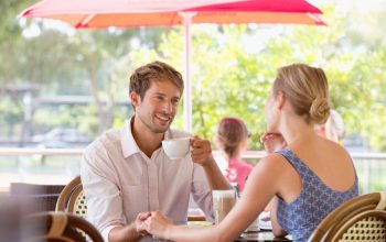 Couple enjoying coffee at an outdoor café terrace under a red parasol in the UAE